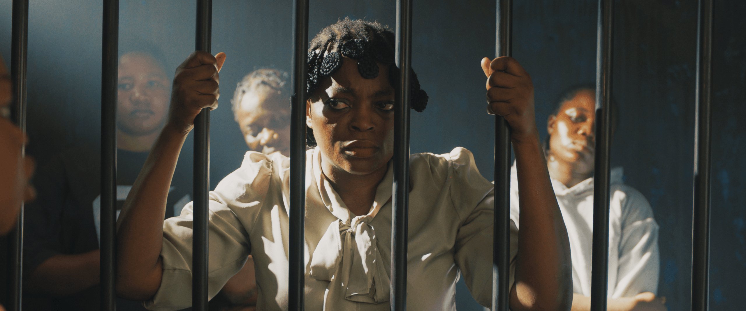 A woman standing behind detention bars